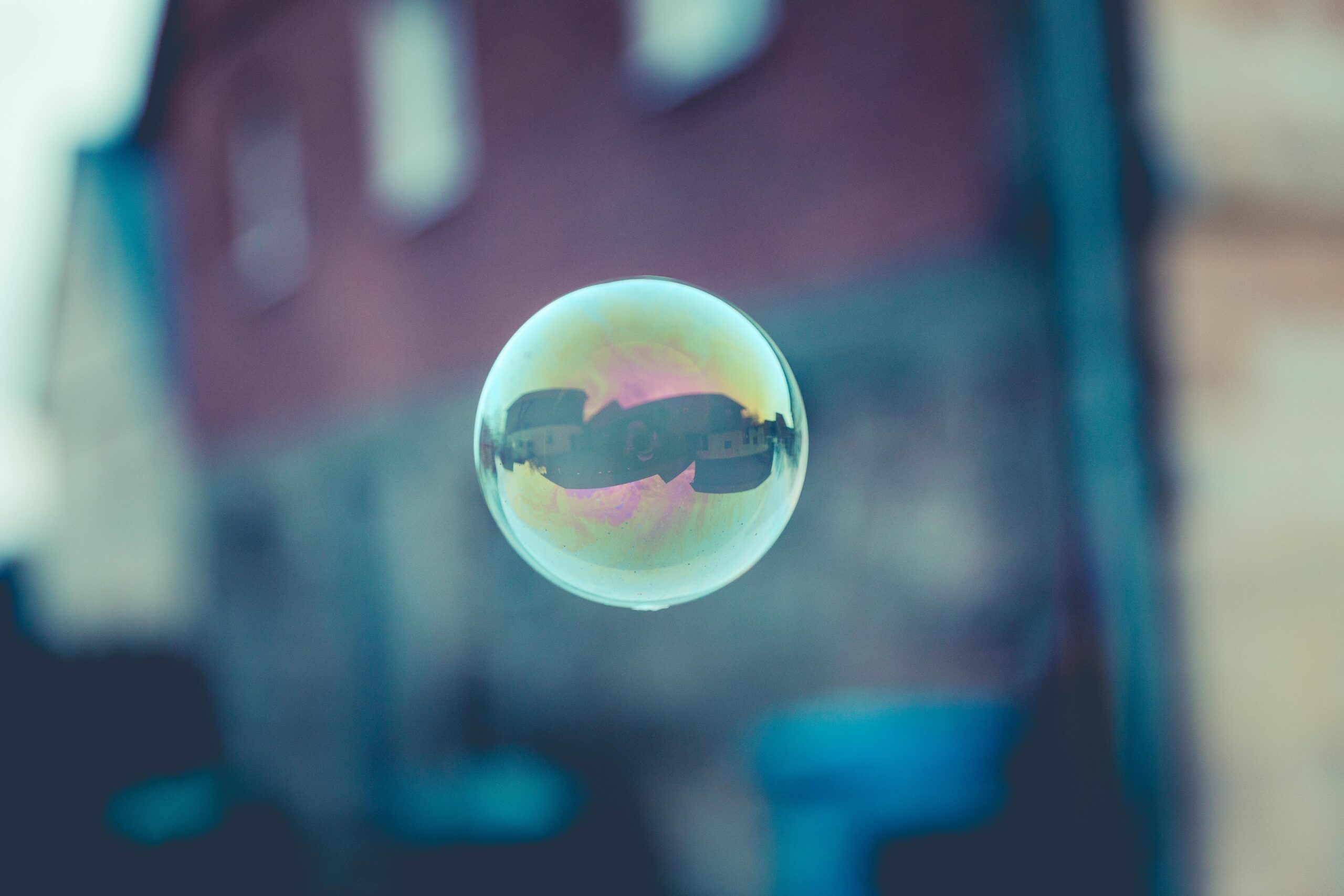 A single soap bubble reflecting buildings in an urban setting with a blurred background.